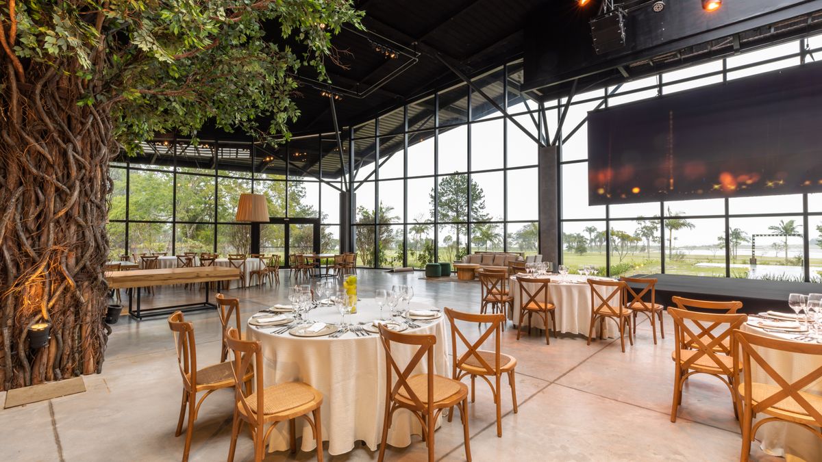 Spacious restaurant interior featuring modern decor, a large screen, and beautifully arranged tables for an elegant event.