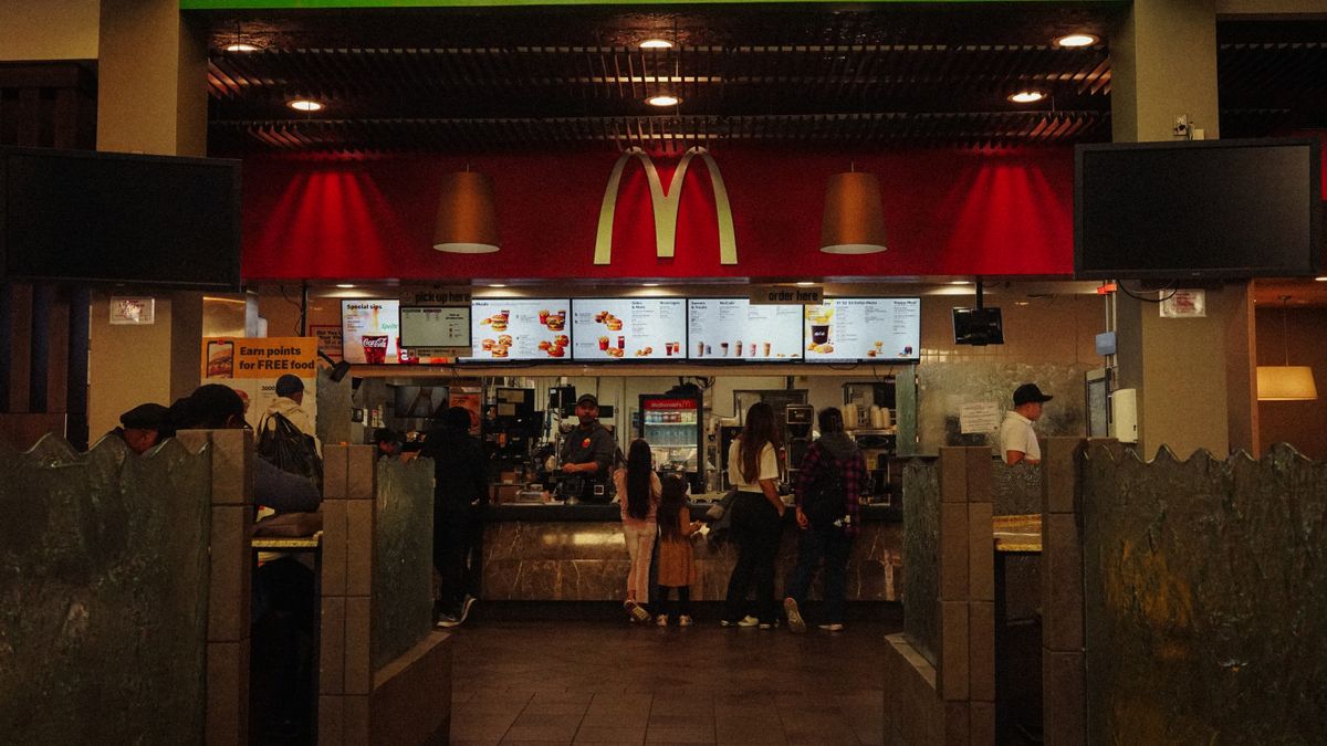A bustling scene at a McDonald's restaurant counter with customers and staff in an indoor setting.
